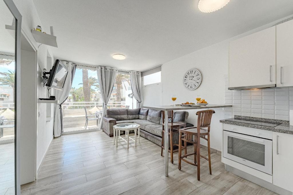 a kitchen and living room with a couch and a table at Primavera Tranquil Retreat 2-Bedroom Apartment with Balcony, Garden View & Fiber WiFi in Arona