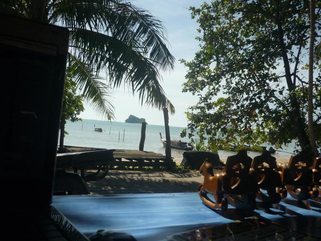 a group of people sitting on a table near the beach at Pasai Beach Lodge in Ko Yao Noi