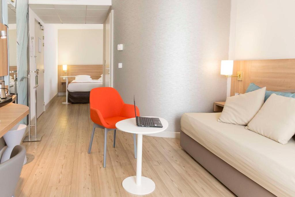 a room with a bed and a desk with a laptop on a table at Best Western Plus Ajaccio Amirauté in Ajaccio