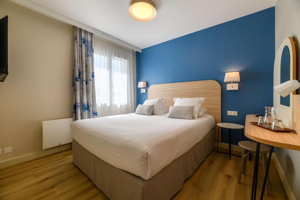 a bedroom with a large bed and a blue wall at Best Western Plus Ajaccio Amirauté in Ajaccio