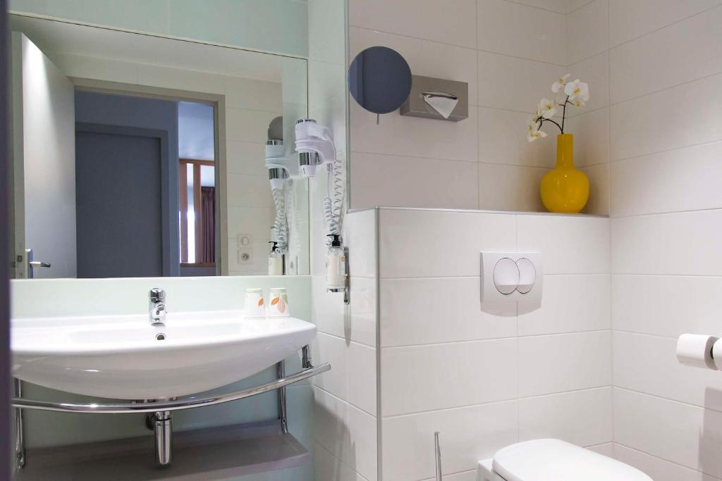 a white bathroom with a sink and a mirror at Best Western Plus Ajaccio Amirauté in Ajaccio
