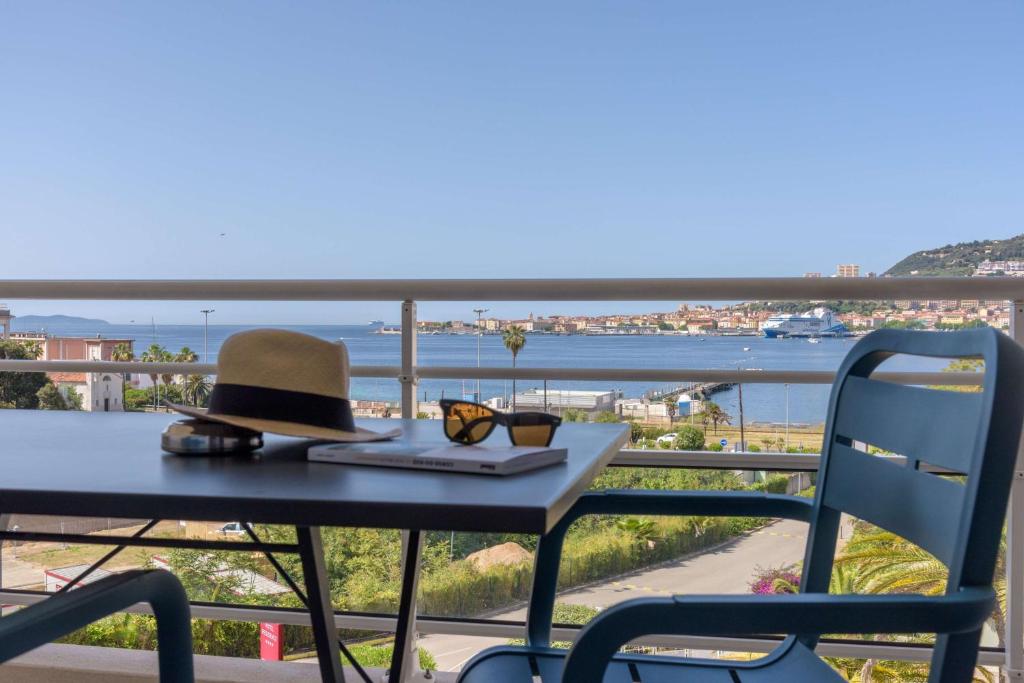 a hat and glasses sitting on a table on a balcony at Best Western Plus Ajaccio Amirauté in Ajaccio
