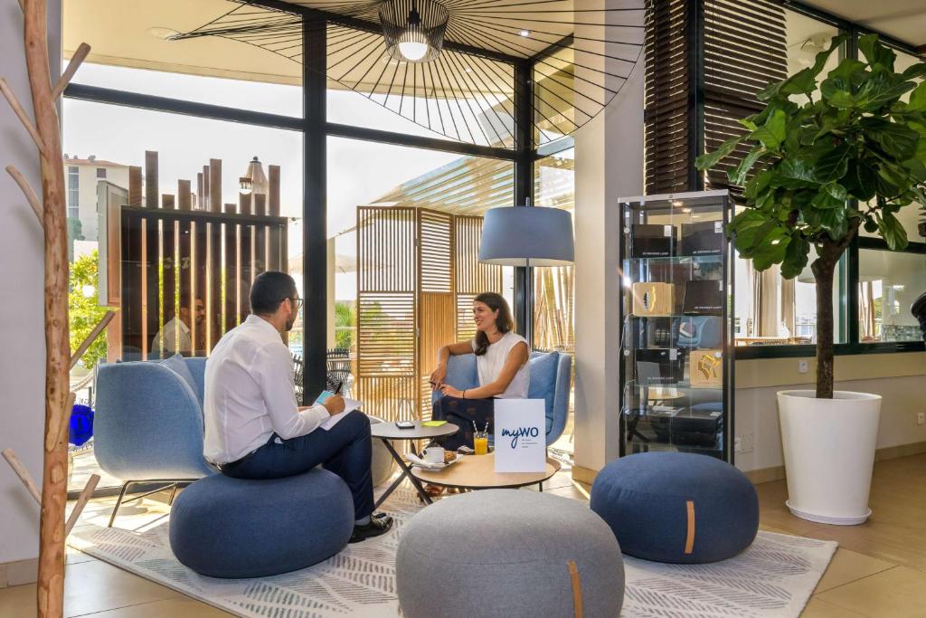 two people sitting in an office with chairs and tables at Best Western Plus Ajaccio Amirauté in Ajaccio