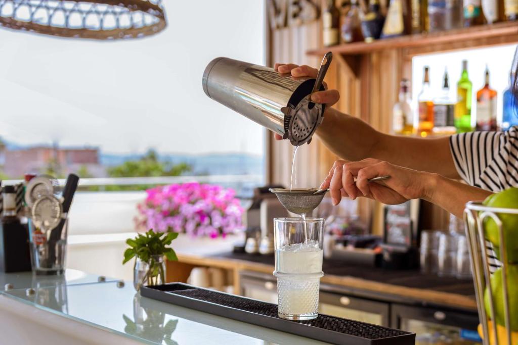 a woman is making a drink in a bar at Best Western Plus Ajaccio Amirauté in Ajaccio