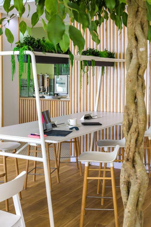 a table and chairs with a tree in a room at Best Western Plus Ajaccio Amirauté in Ajaccio