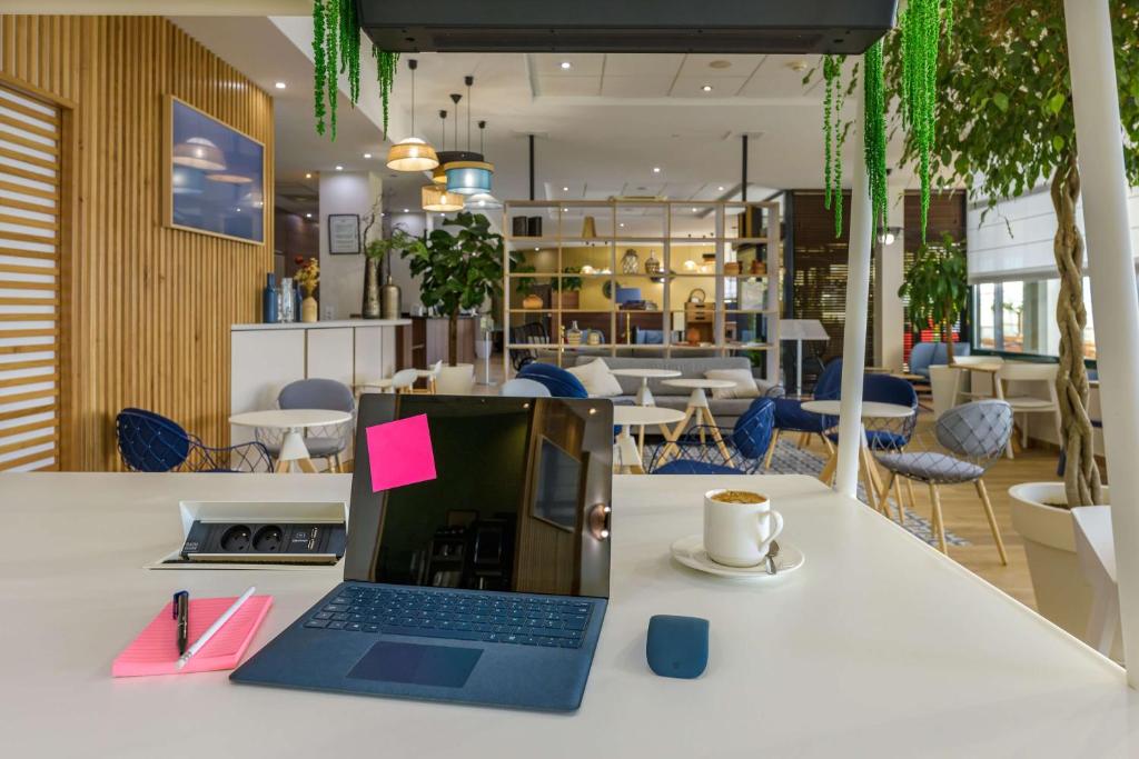 a laptop sitting on a table with a cup of coffee at Best Western Plus Ajaccio Amirauté in Ajaccio