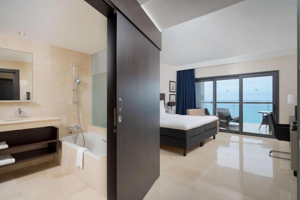 a hotel room with a bed and a tub and a bathroom at Radisson Blu Resort Gran Canaria in La Playa de Arguineguín