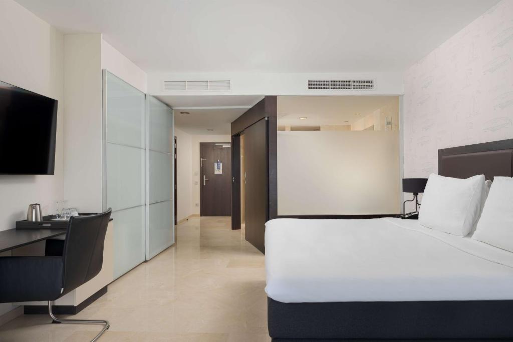 a hotel room with a white bed and a desk at Radisson Blu Resort Gran Canaria in La Playa de Arguineguín