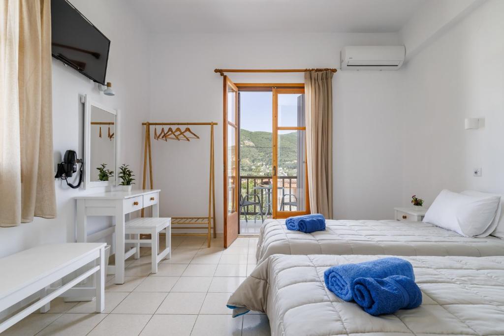 a bedroom with two beds and a desk and a window at White Lily in Skopelos Town