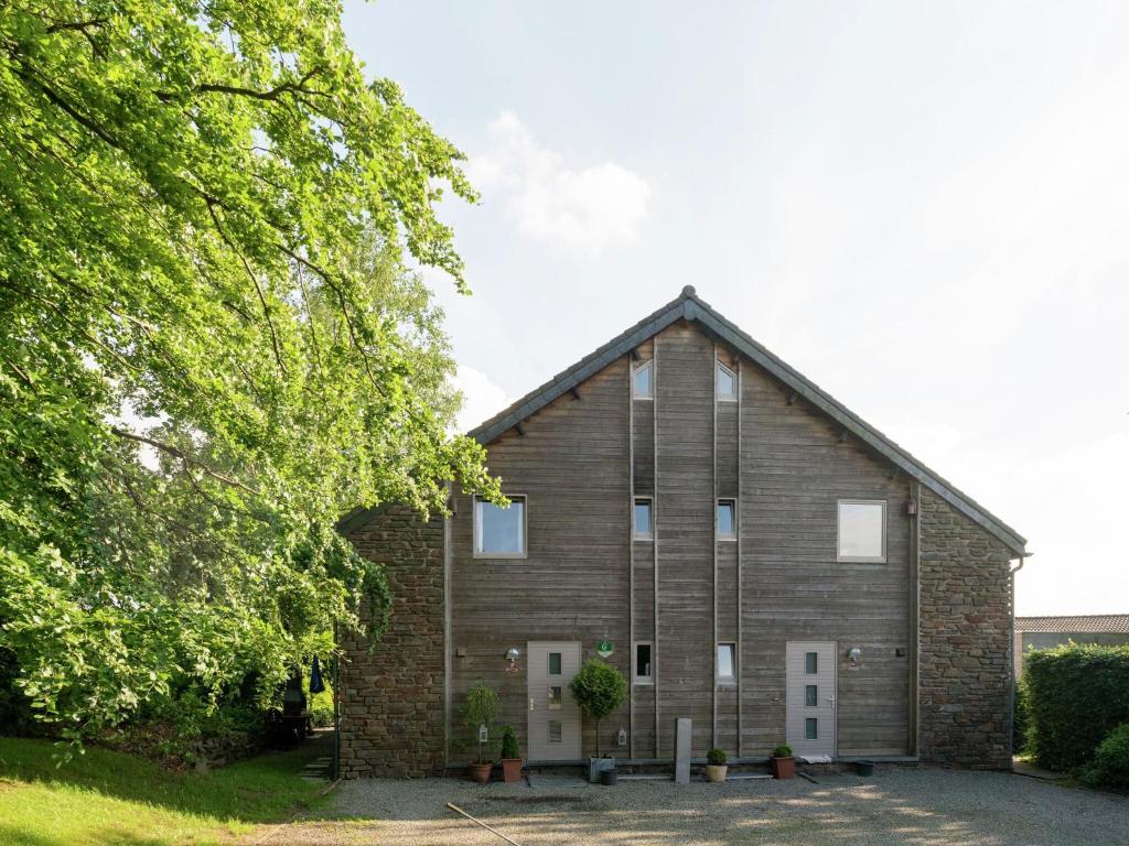 eine alte Backsteinkirche mit einem Baum in der Unterkunft Cozy Holiday Home with Jacuzzi and Sauna in Ovifat in Longfaye
