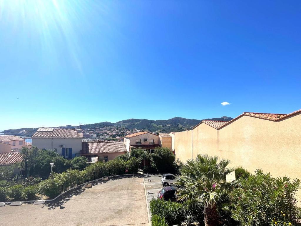 - une vue sur une ville avec des bâtiments et des palmiers dans l'établissement Banyuls-sur-Mer : Duplex T3 avec terrasse, parking privé, proche plage - FR-1-309-77, à Banyuls-sur-Mer