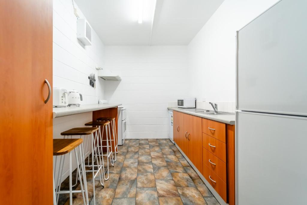 a kitchen with wooden cabinets and a refrigerator at YHA Thredbo in Thredbo