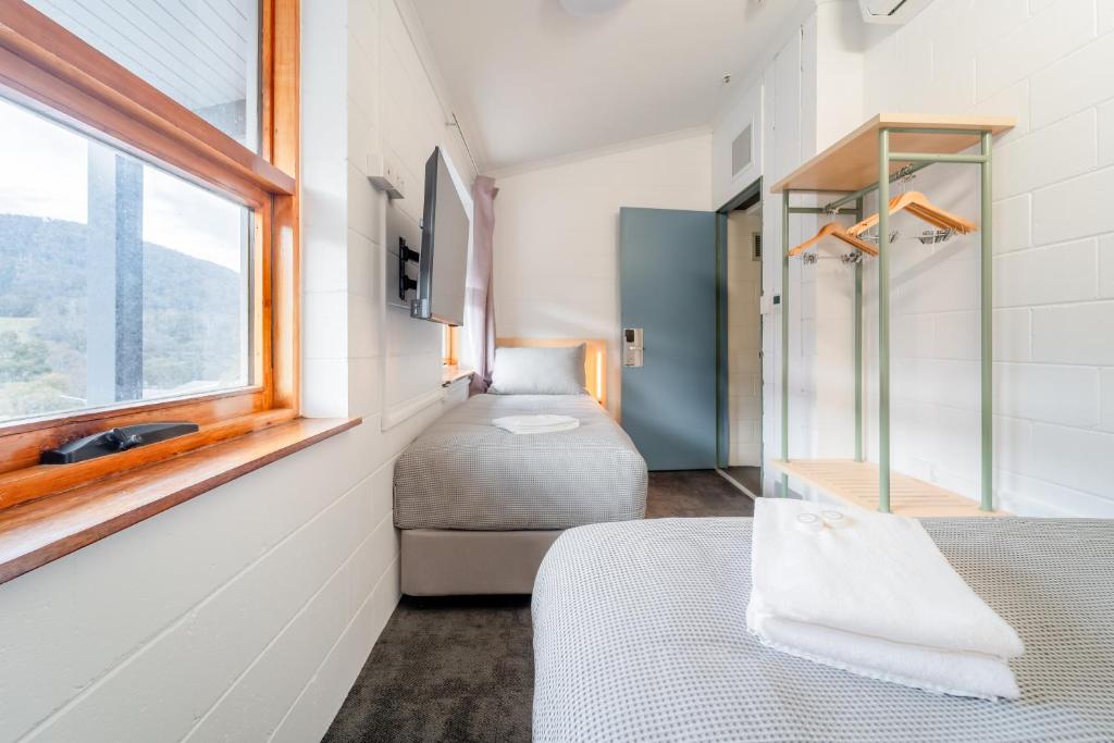 a small room with two beds and a window at YHA Thredbo in Thredbo