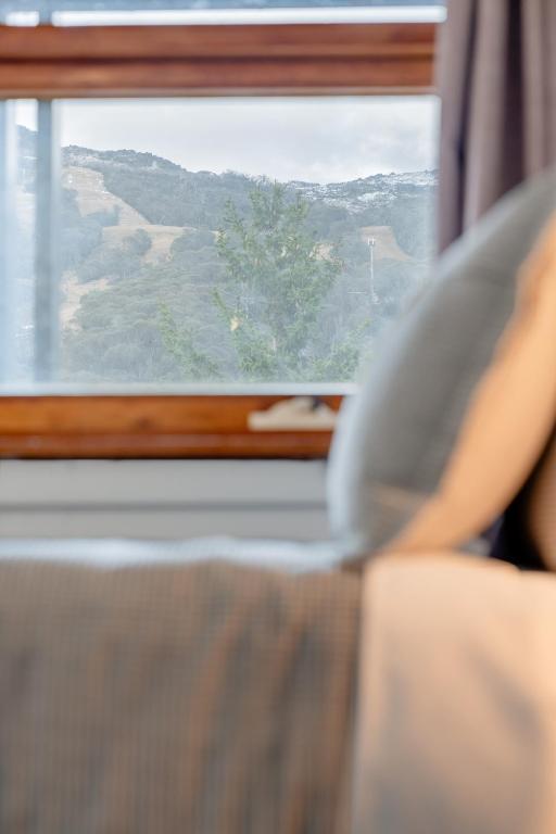 a person laying on a bed looking out a window at YHA Thredbo in Thredbo
