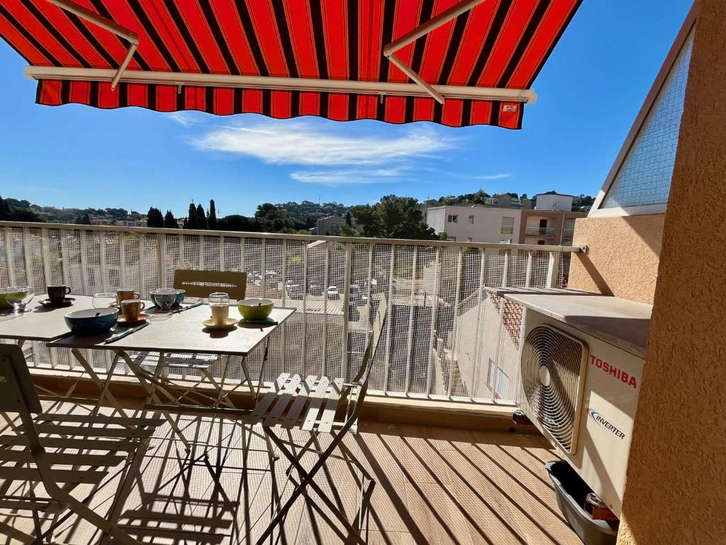 un balcon avec une table, des chaises et un parasol dans l'établissement Studio rénové 4 pers à Cavalaire-sur-Mer avec balcon et parking - FR-1-226B-190, à Cavalaire-sur-Mer