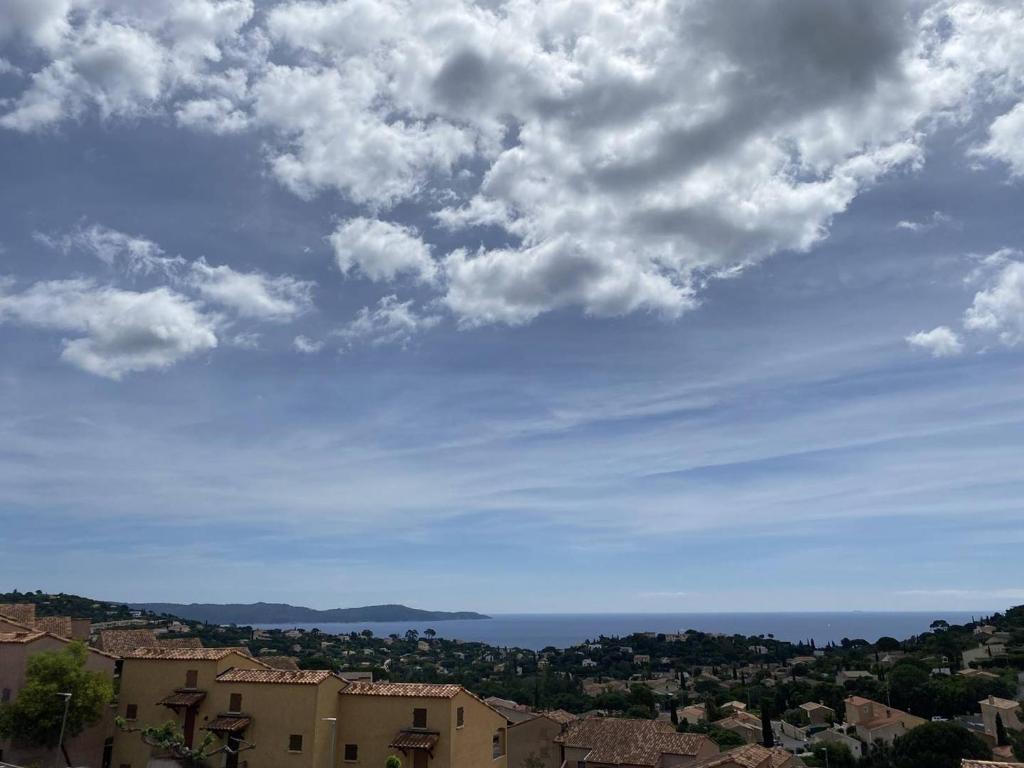 une vue de l'océan depuis une ville sous un ciel nuageux dans l'établissement Appartement avec piscine et parking à Cavalaire-sur-Mer - FR-1-100-341, à Cavalaire-sur-Mer