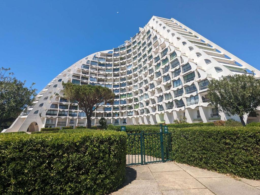 un grand bâtiment blanc devant une haie dans l'établissement T4 spacieux avec terrasse et vue panoramique, parking inclus - FR-1-250-286, à La Grande Motte