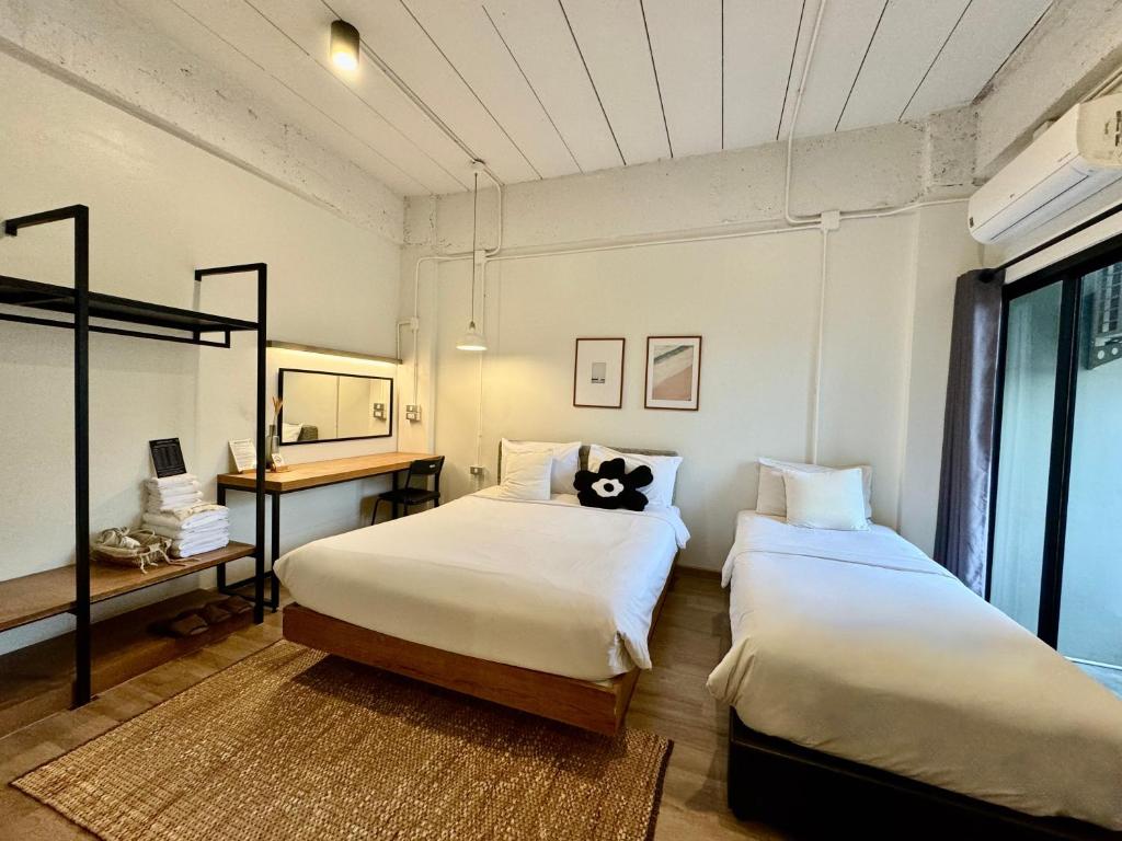 a bedroom with two beds and a desk and a window at The51Hometel in Chiang Mai