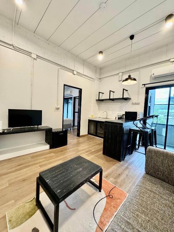 An open-plan living area with a sofa, television, kitchen, and dining counter.