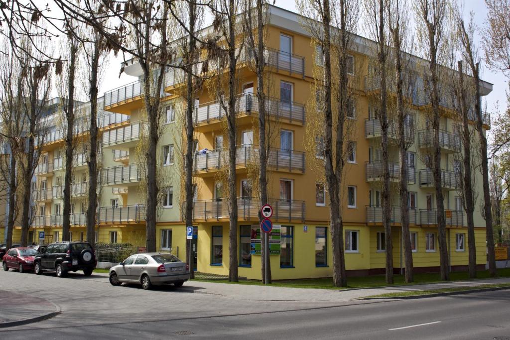 コウォブジェクにある100-SIO Apartamentyの車が目の前に停まった黄色い建物