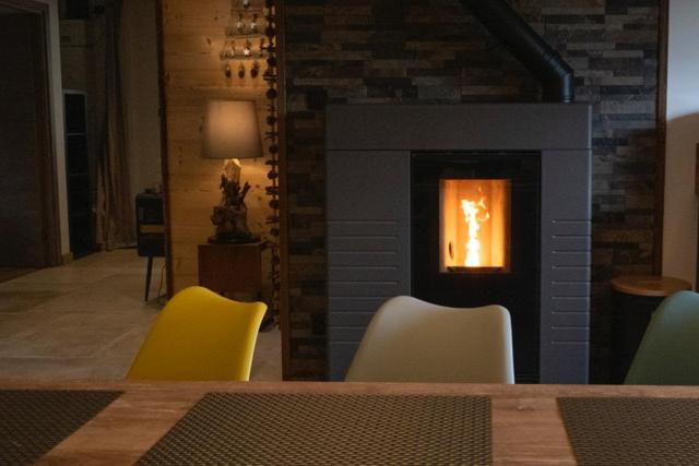 une salle à manger avec une cheminée et des chaises jaunes dans l'établissement Chalet COCOTTE - pétanque, jacuzzi & baby-foot, à Xonrupt-Longemer
