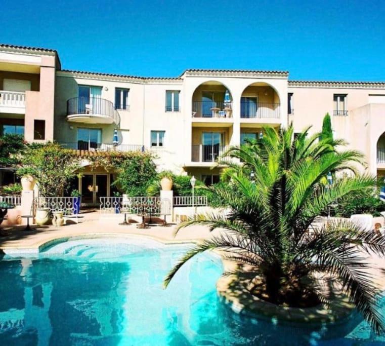 un palmier en face d'un bâtiment avec piscine dans l'établissement Studio, Piscine, tennis, à Saint-Tropez