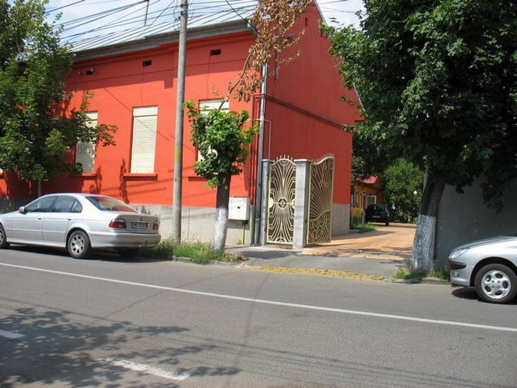 特爾古穆列什的住宿－Noroc si Fericire，两辆汽车停在一座红色建筑前面