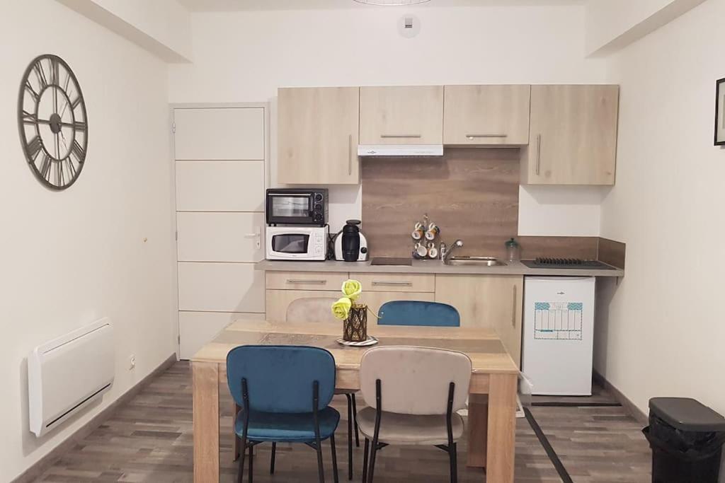une cuisine avec une table en bois et des chaises bleues dans l'établissement Studio en plein centre Valence, à Valence