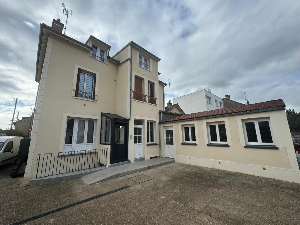 une grande maison blanche avec un parking dans l'établissement Appartement Champagne sur Seine, à Champagne-sur-Seine