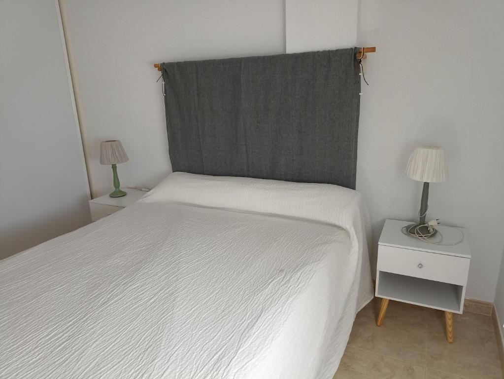 sypialnia z białym łóżkiem i 2 lampami w obiekcie Apartamento en zona Atalaya con garaje y WIFI w mieście Conil de la Frontera