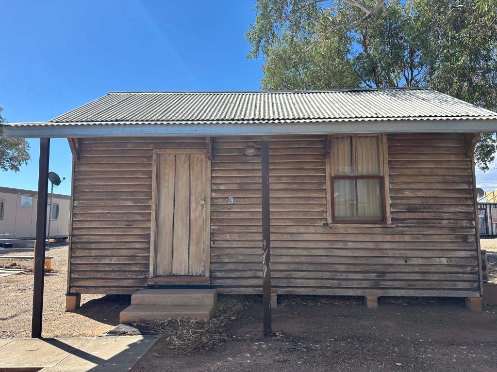 una piccola casa in legno con porta e finestre di Parachilna Overflow Accommodation a Flinders Ranges
