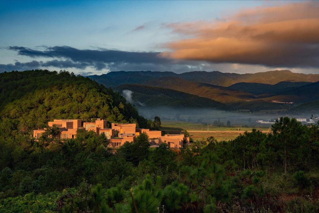 Diannan喜林苑沙溪夯土酒店的山丘上的建筑,背景是山脉