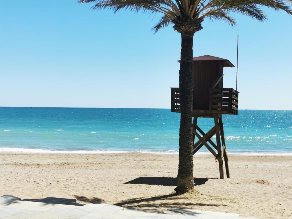 ビナロスにあるLa casa de Mumuのライフガードスタンドのあるビーチのヤシの木