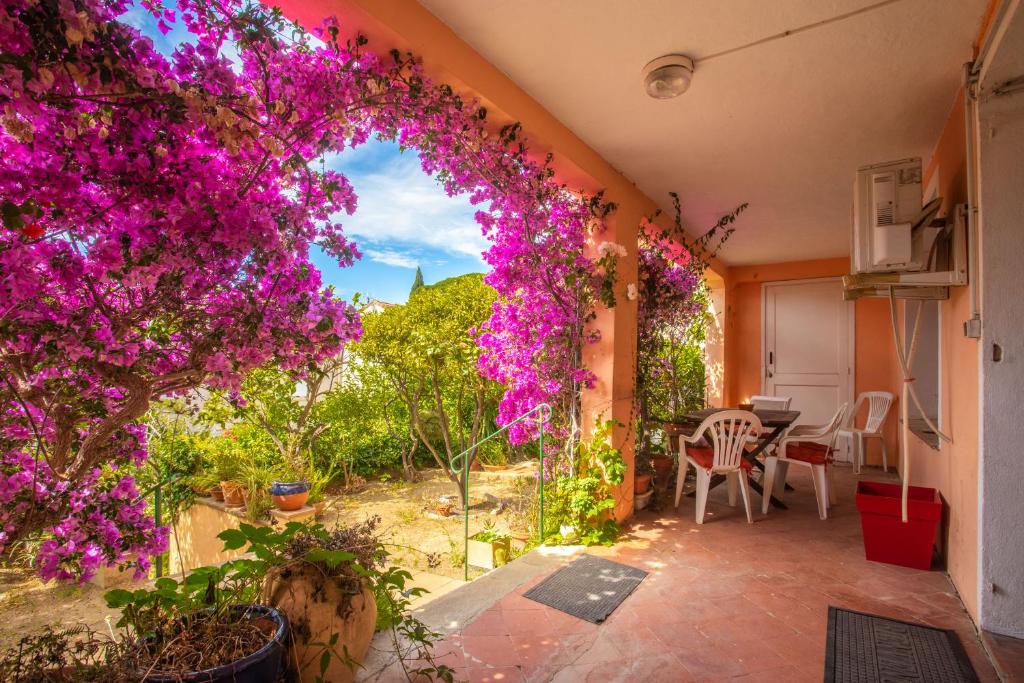 a patio with purple flowers and a table and chairs at Appartement climatisé au Lavandou in Le Lavandou