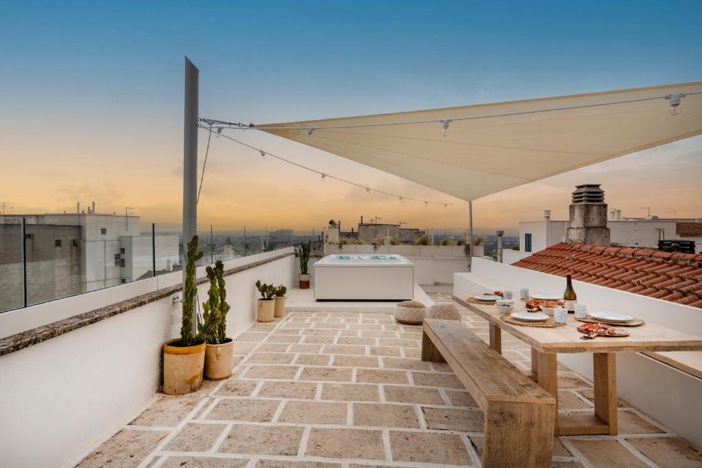 un patio con una mesa de madera en el techo en Casa u Bùrie, casa design con terrazza panoramica e jacuzzi, en Cisternino