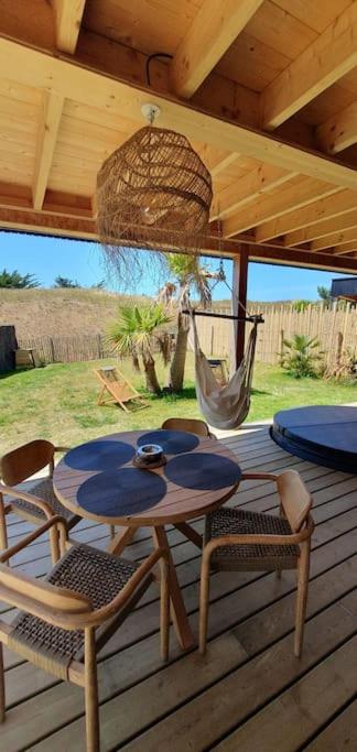 d'une terrasse avec une table, des chaises et un hamac. dans l'établissement Maison de plage Manoga, à Saint-Germain-sur-Ay