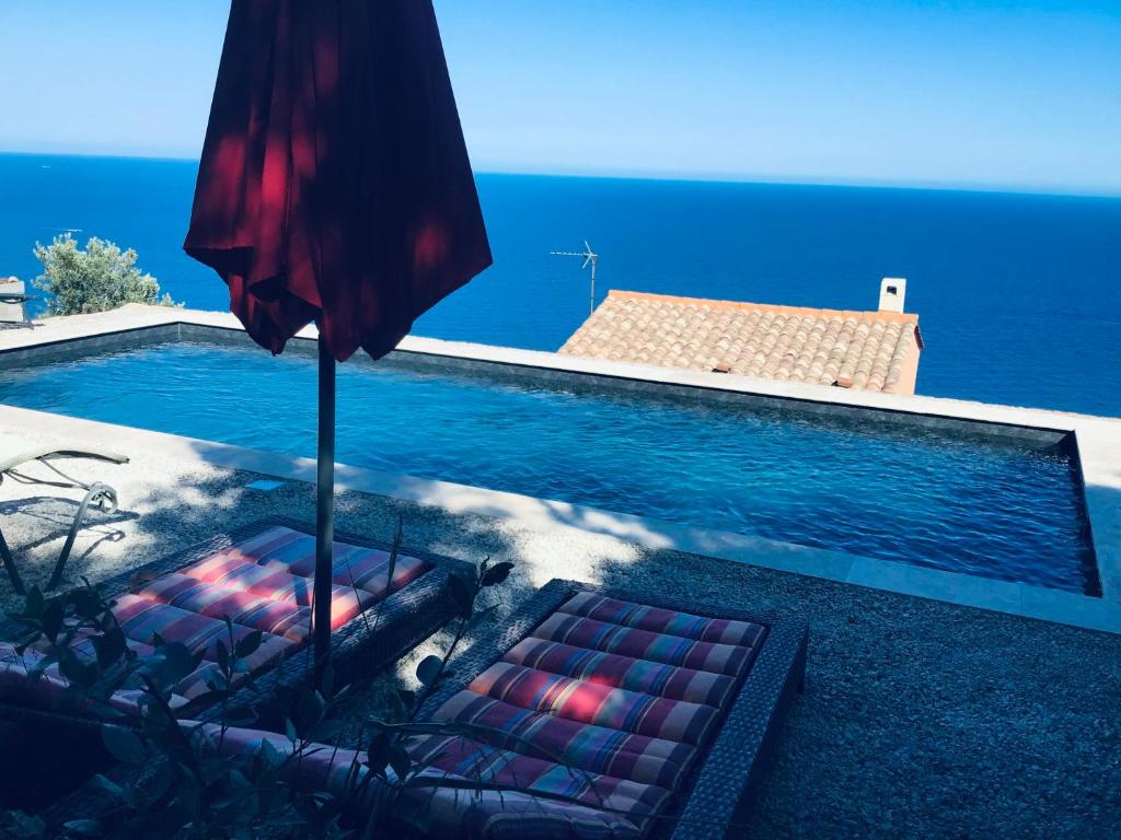 une piscine avec deux chaises et un parasol dans l'établissement Belle Villa VUE MER EXCEPTIONNELLE PISCINE PRIVÉE 3 mn PLAGES et CALANQUES, à Anthéor