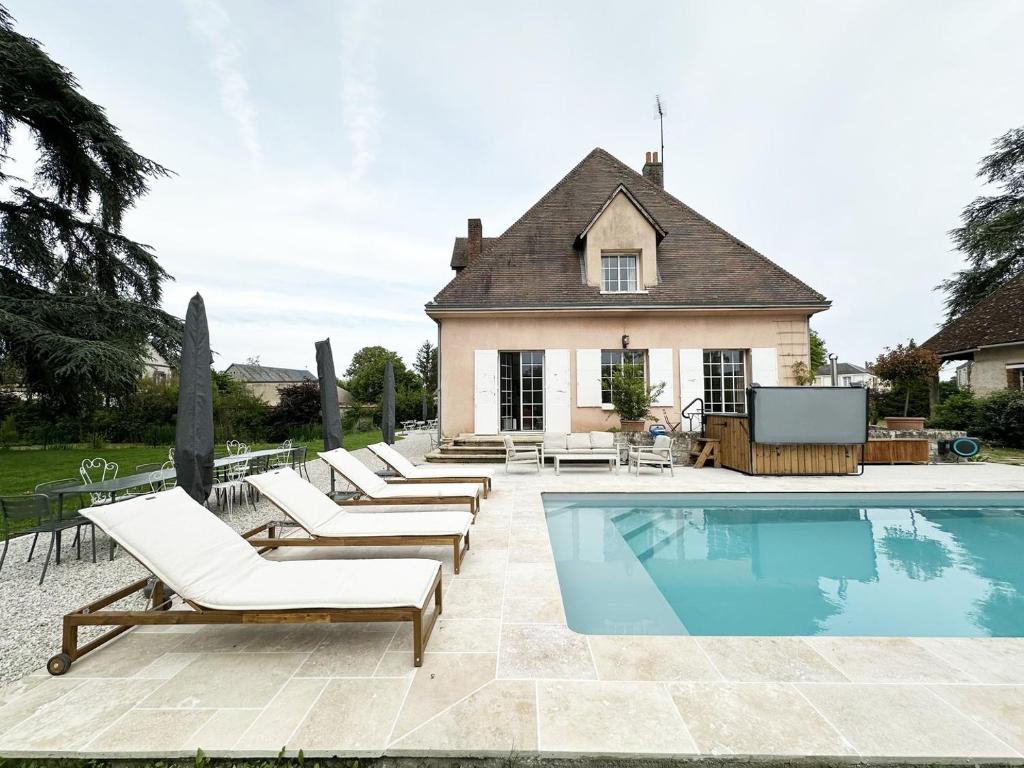 a swimming pool with lounge chairs and a house at La Meslaysienne - Comfortable house, swimming pool in Meslay-le-Vidame