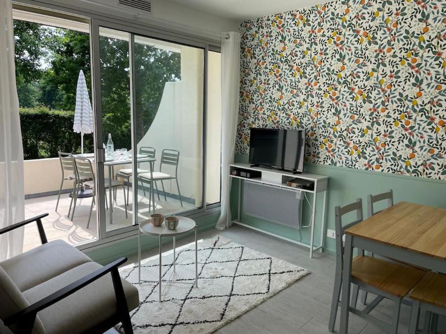 un salon avec une télévision et une table avec des chaises dans l'établissement L'Oranger, à Beg-Meil