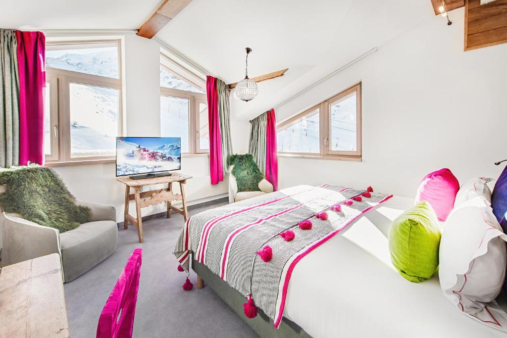 a bedroom with a bed and a tv and windows at Hotel Pashmina Le Refuge in Val Thorens
