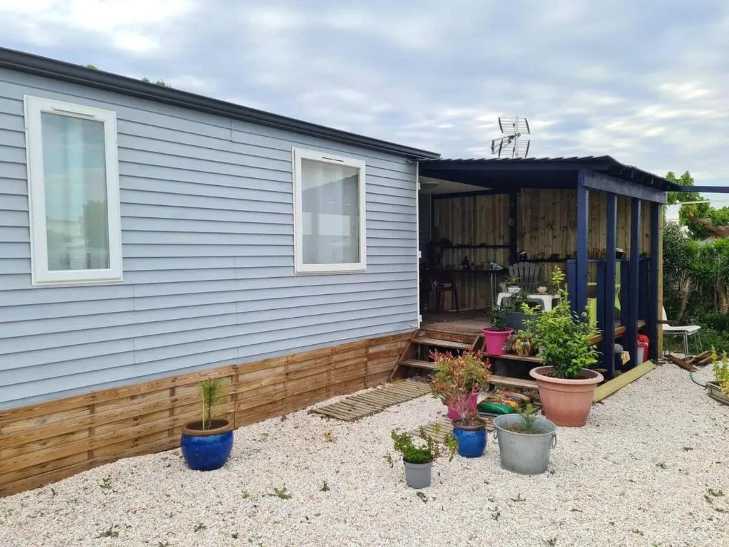 une maison avec des plantes en pot devant dans l'établissement Bungalow charmant à Sigean avec piscine et jardin clôturé, à Sigean