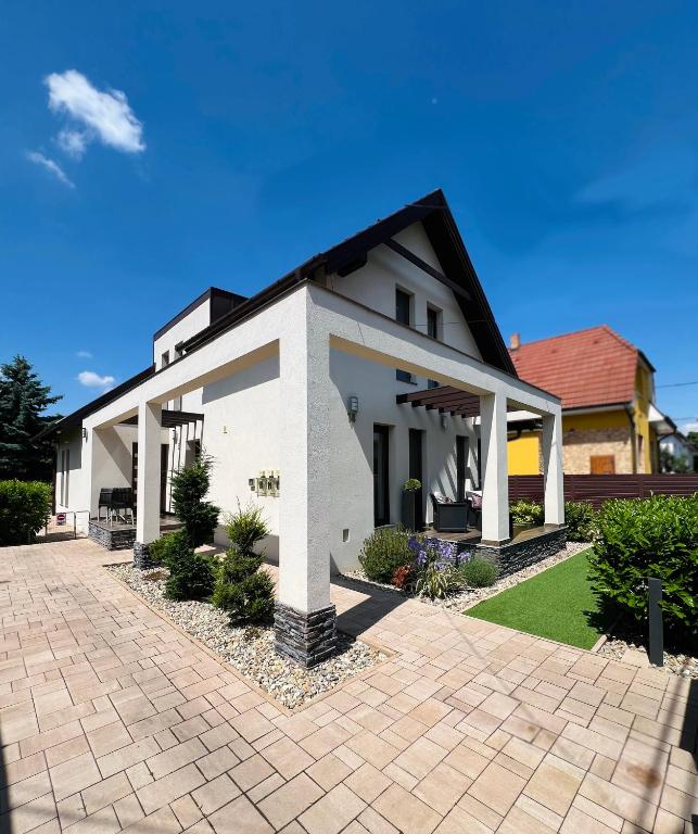 a white house with a brick driveway at True Gem at the Airport by NW Apartments in Budapest