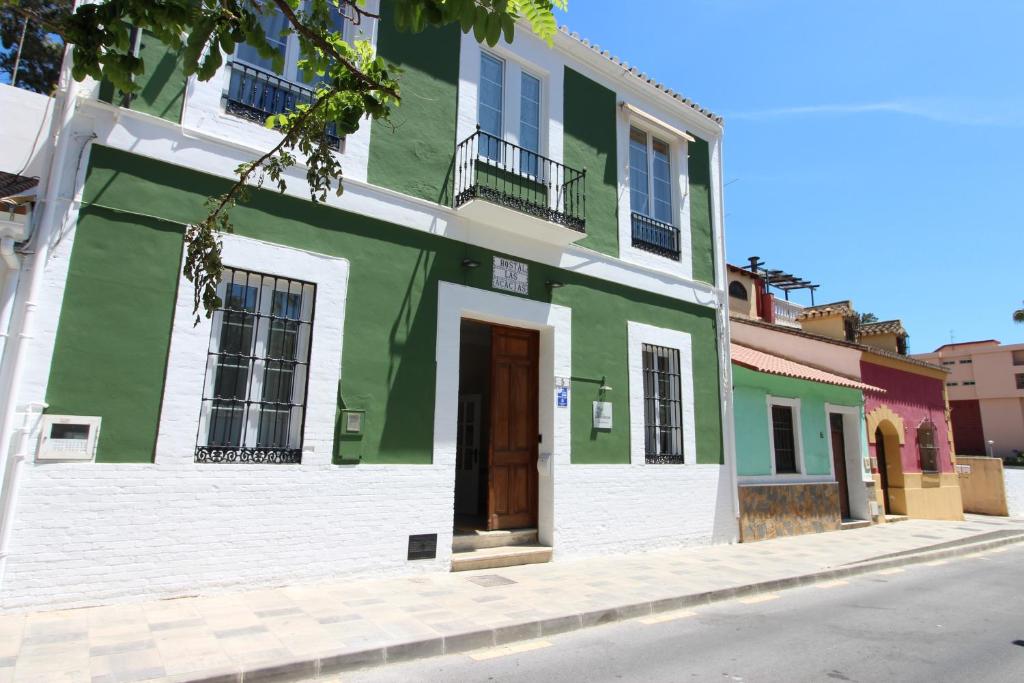 a green and white building with a door on a street at Hostal Las Acacias in Málaga