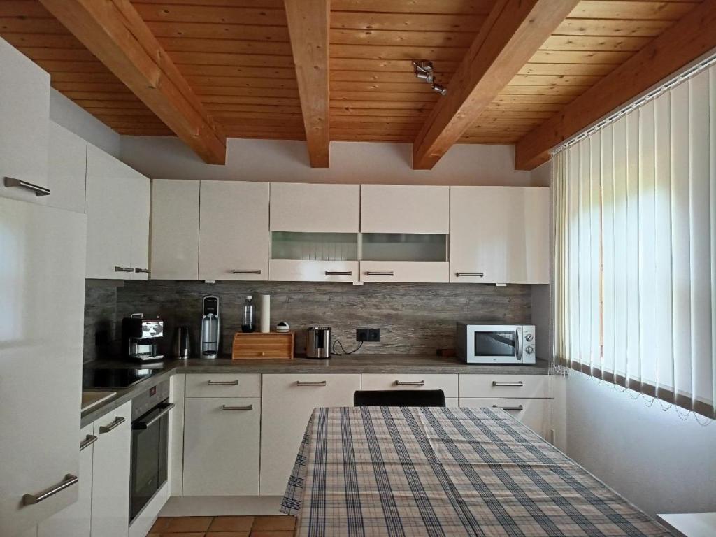 レーゲンにあるFerienhaus Virzi - Waldferiendorf Regenの白いキャビネットと木製の天井が備わるキッチン
