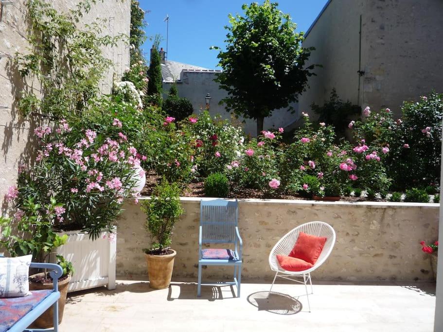 two chairs sitting in a garden with pink flowers at Les Pensées - Chambre Turner in Orléans
