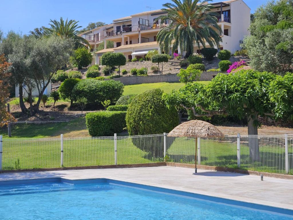 une piscine avec une clôture et un bâtiment dans l'établissement CARDELLINI 30 - Piscine en résidence -Vue mer - 2 Personnes, à Kamiesch