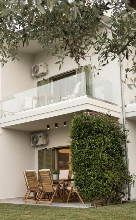 a house with a balcony and chairs and a bush at Villa Elxis in Limenas
