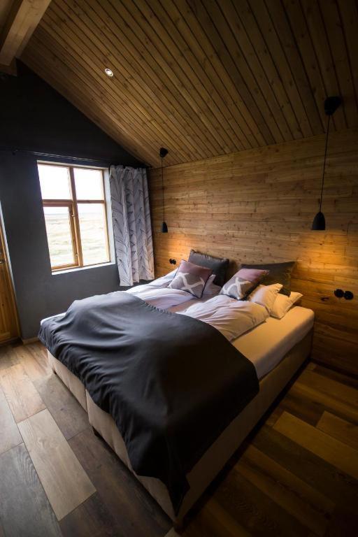 a bedroom with two beds in a wooden wall at Fjalladýrð Guesthouse in Modrudalur