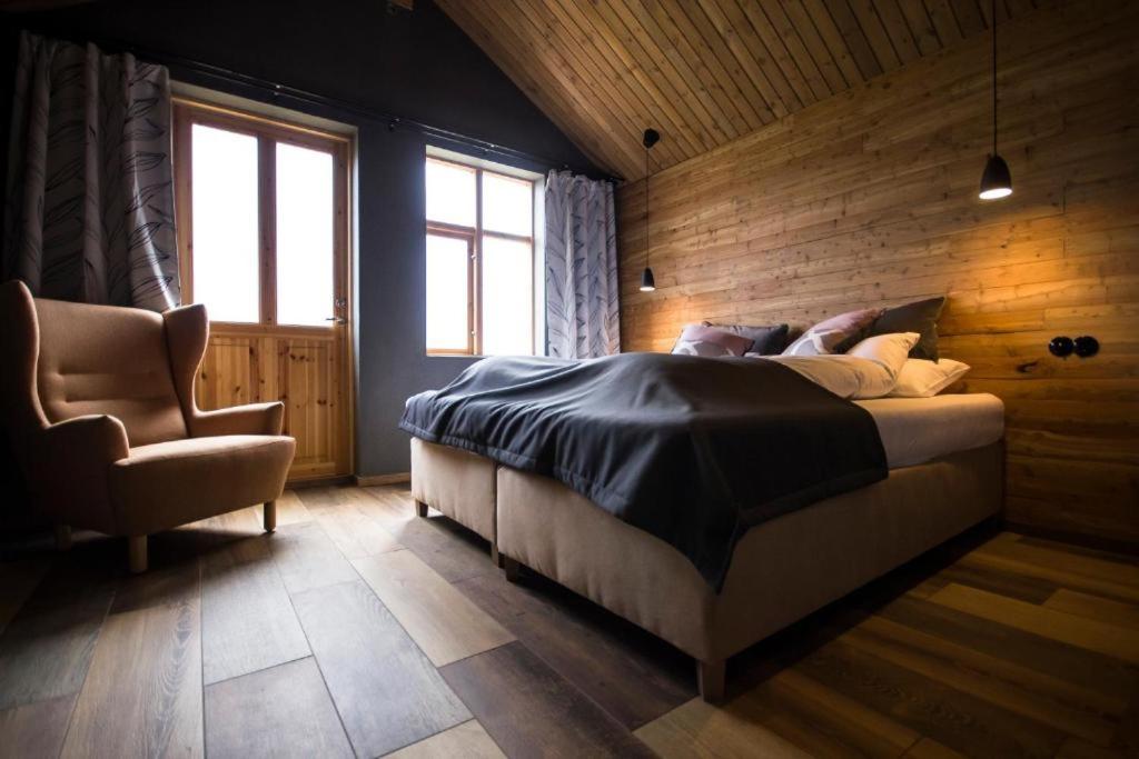 a bedroom with a bed and a chair at Fjalladýrð Guesthouse in Modrudalur