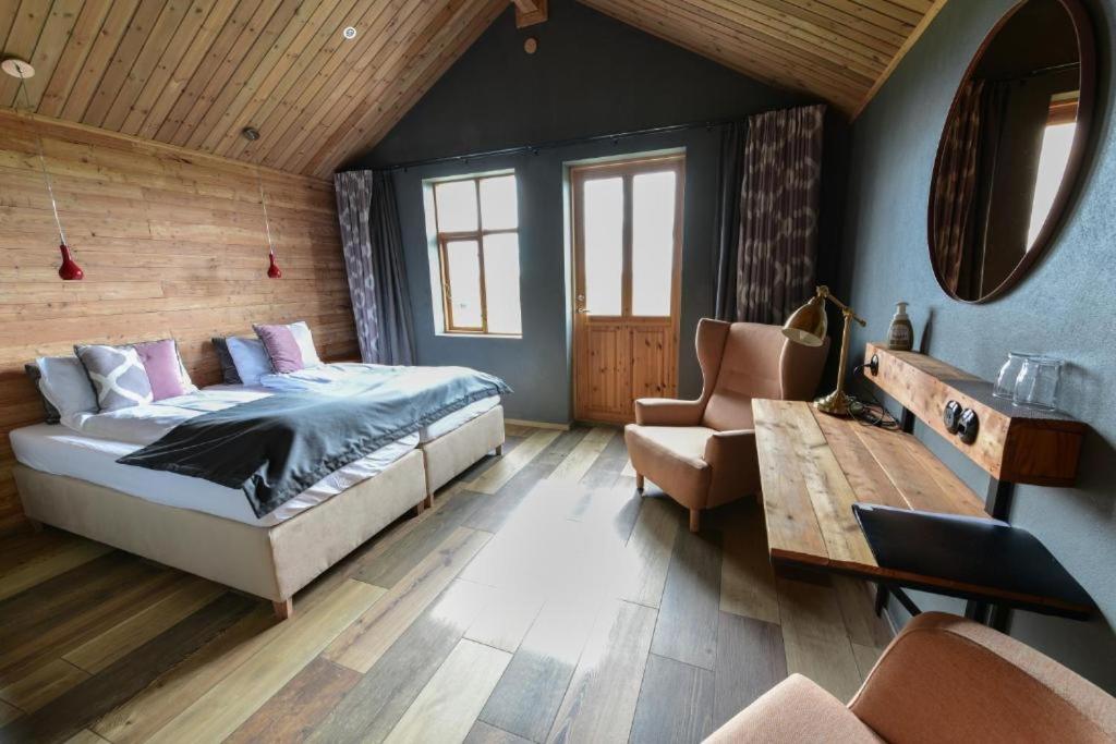 a bedroom with a bed and a couch and a chair at Fjalladýrð Guesthouse in Modrudalur